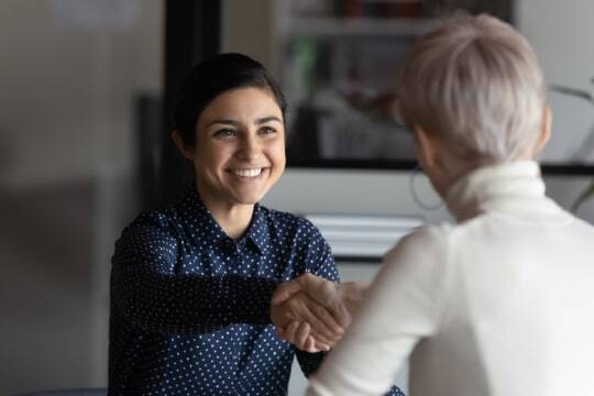 Two seated professional shaking hands.